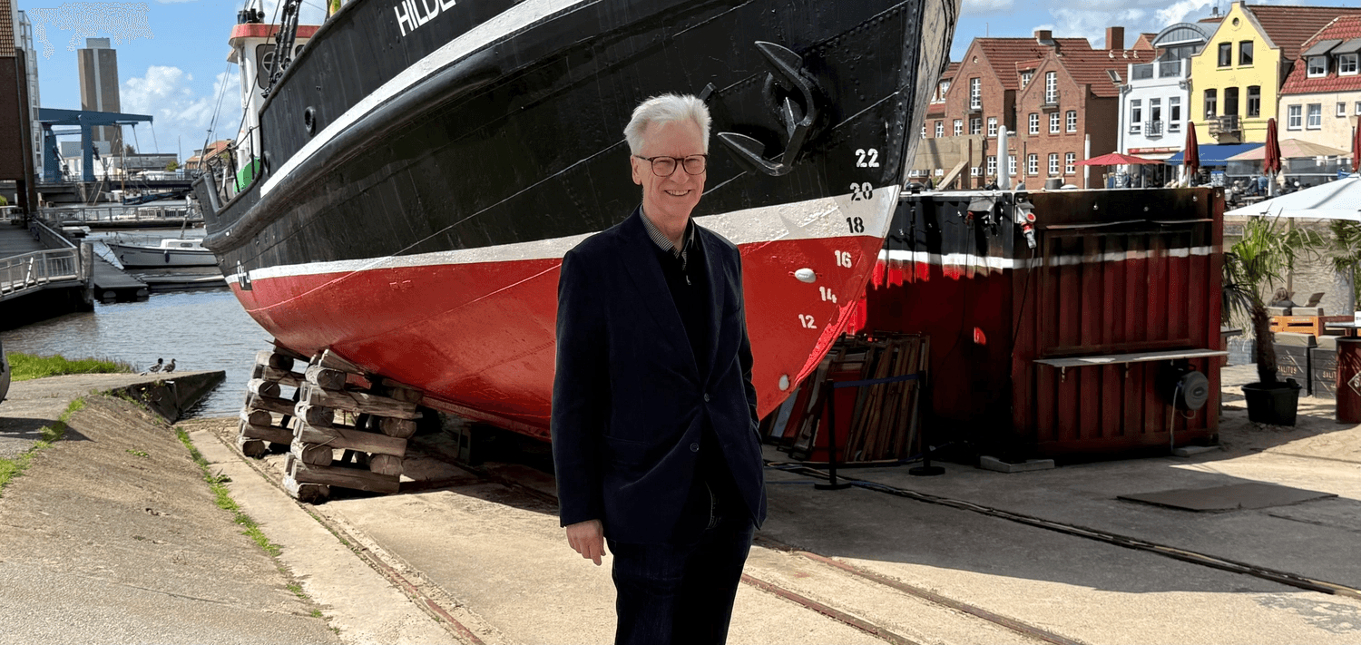 Günther Hansen an einem norddeutschen Hafen, im Hintergrund ein Schiff im Trockendock